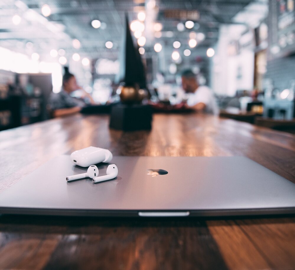 MacBook auf einem dunklen Holztisch mit einem verschwommenen Hintergrund